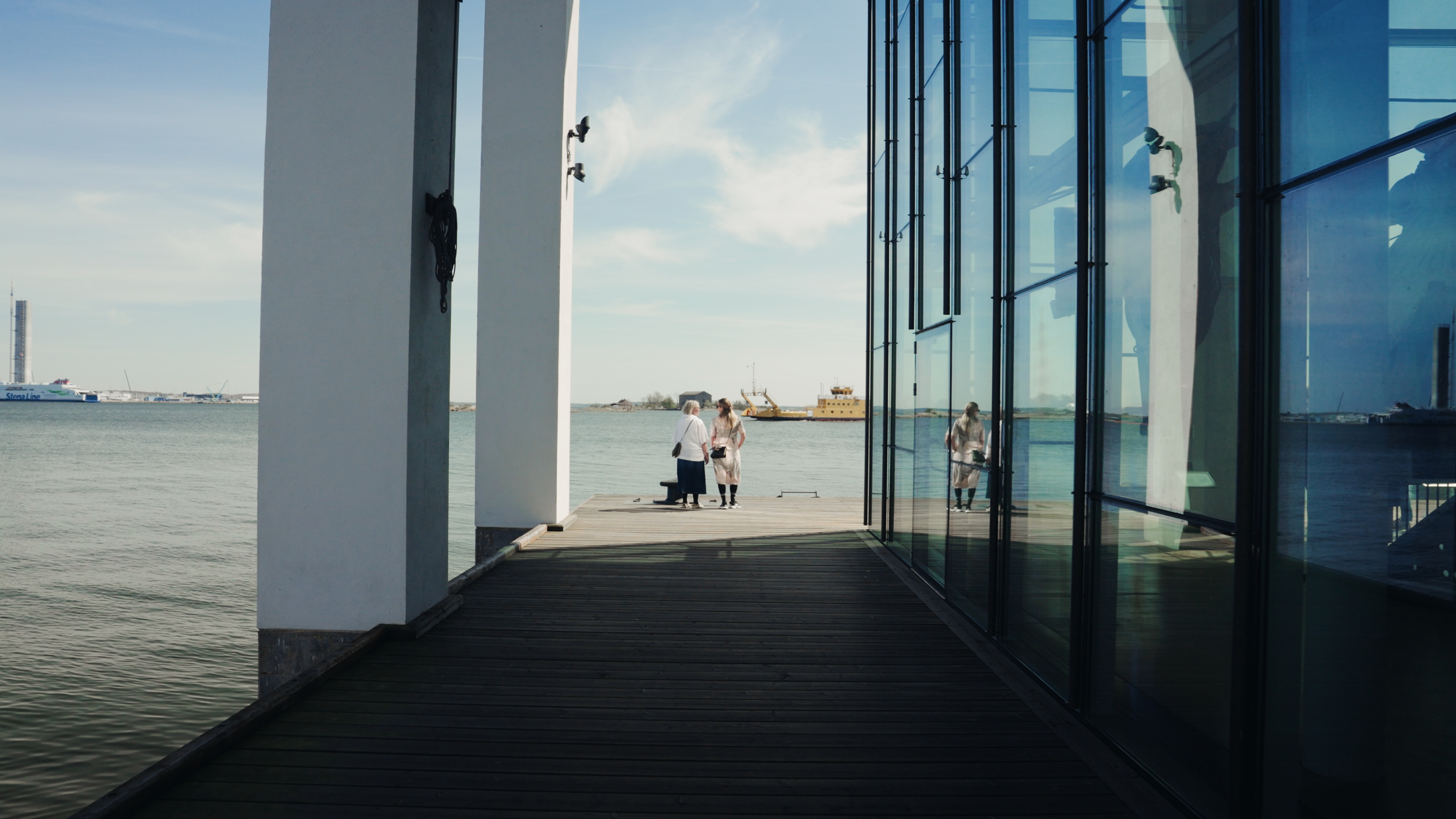 Två vuxna står en pir utanför Marinmuseum och tittar mot vattnet